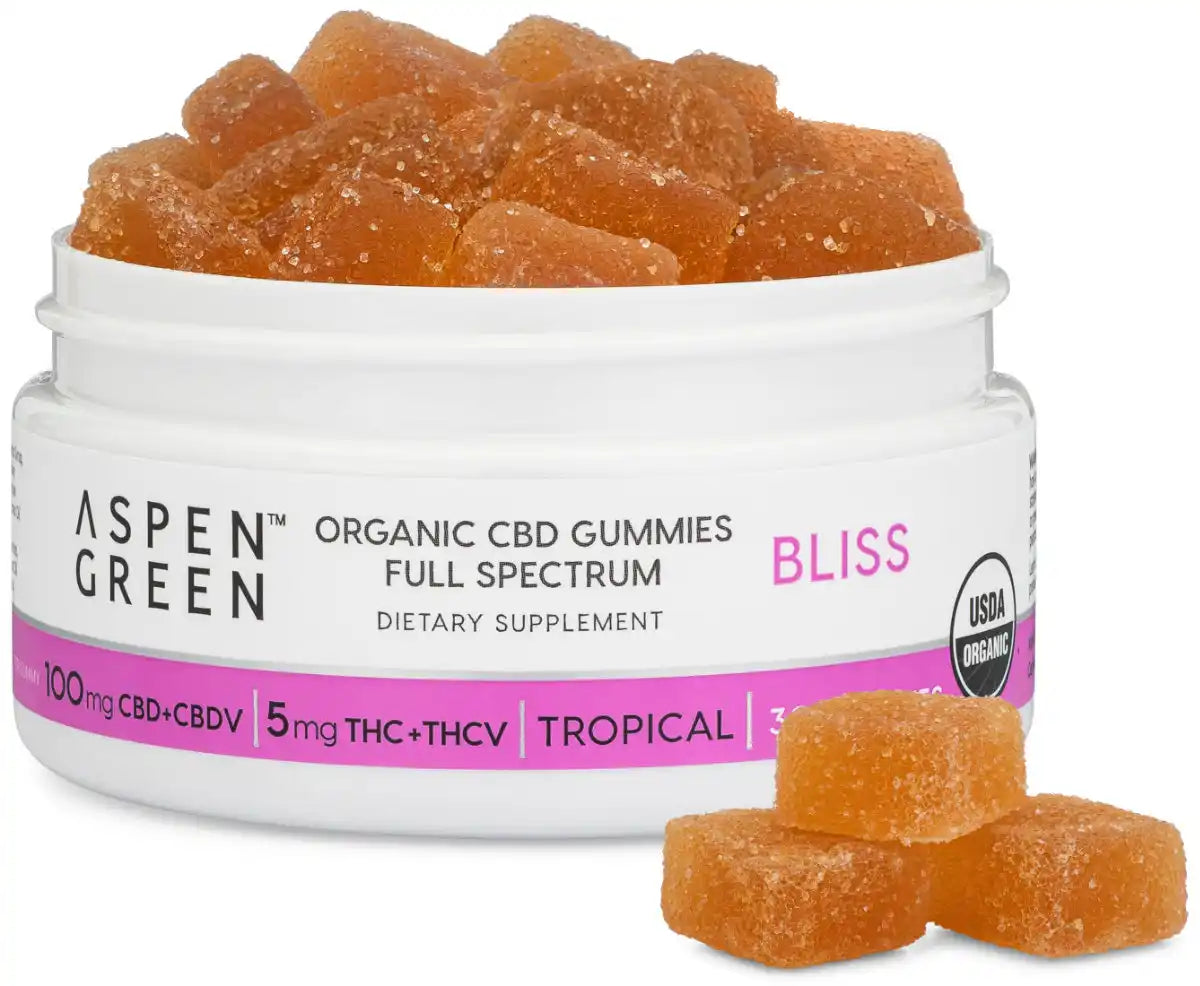 Open jar of Aspen Green Bliss Full Spectrum CBD Gummies with 3 gummies beside it; USDA Certified Organic, 100mg CBD+CBDV, Tropical flavor, 30 count.