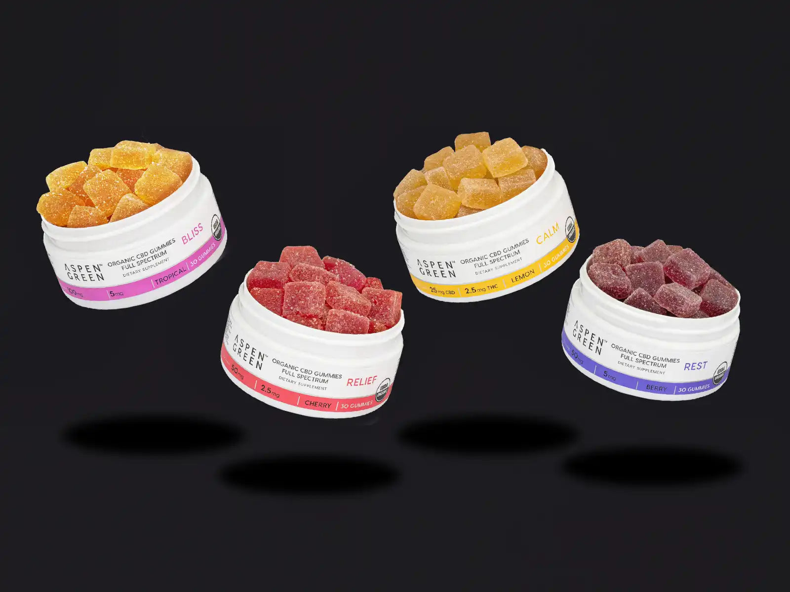 Four jars of Aspen Green CBD gummies on a black background