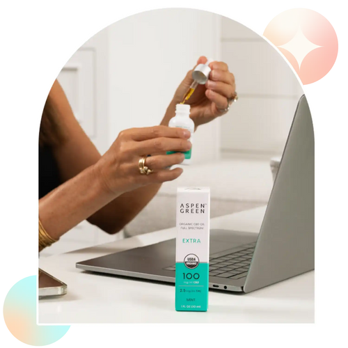 Woman using dropper of Aspen Green Extra Mint CBD Oil at desk