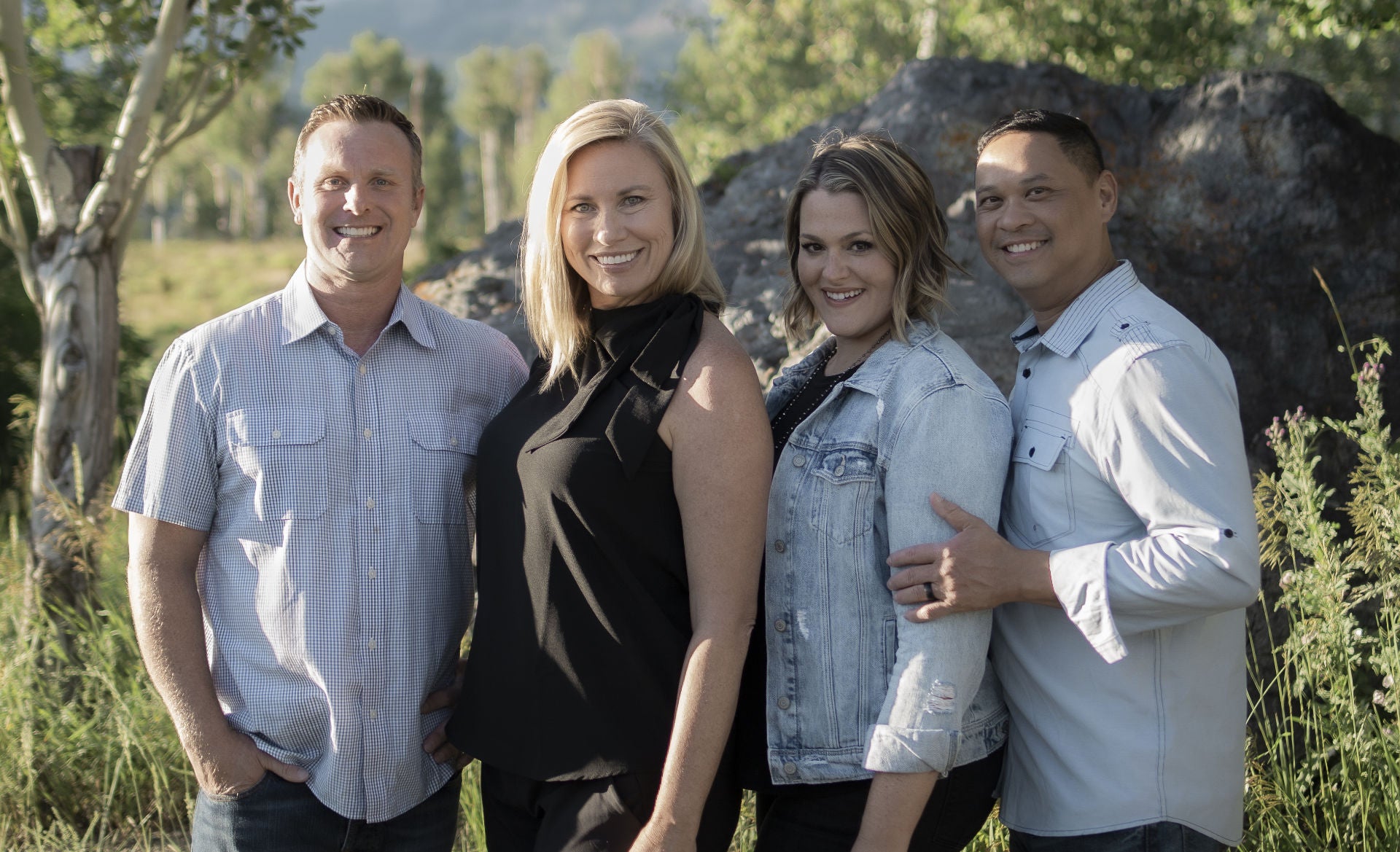 The Lewis and Chong families standing together in a natural setting with trees and rocks in the background