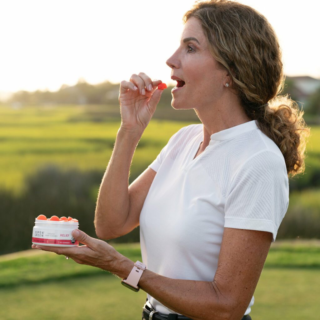 Woman about to eat Aspen Green CBD relief gummy outdoors