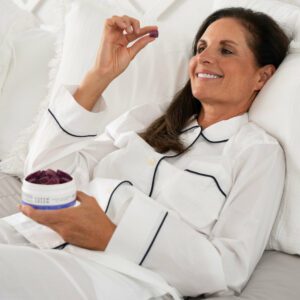 Woman eating Aspen Green Rest gummies in bed